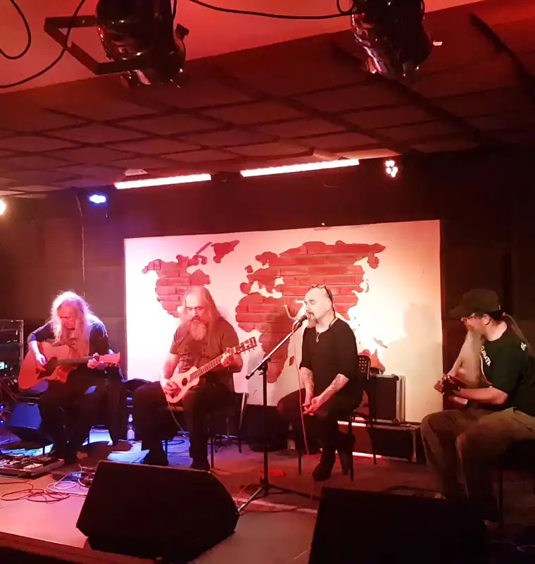 Zespół gra na scenie MJAZZGI na tle ceglanej mapy świata w czerwonym świetle