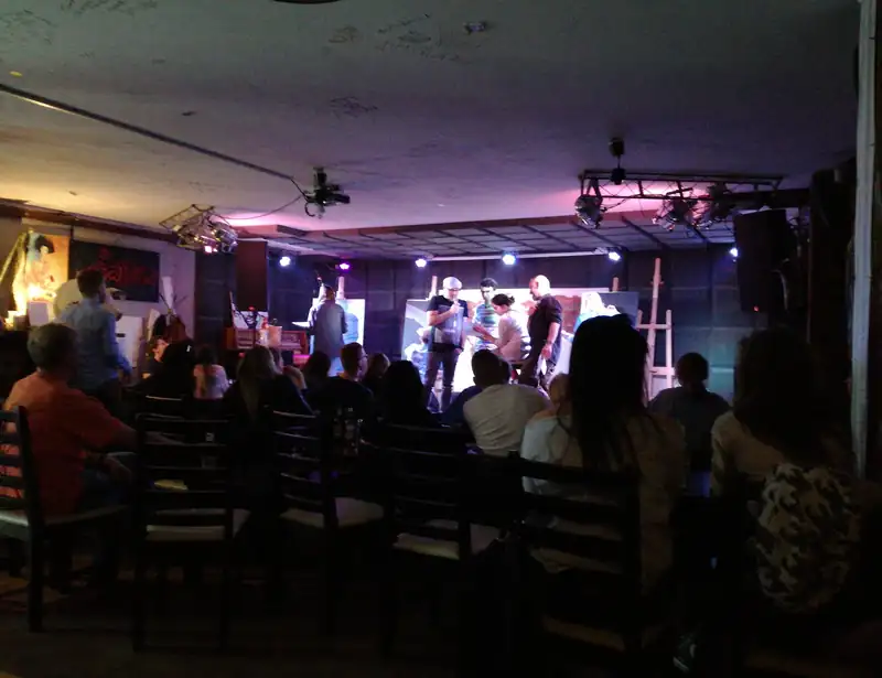 Pełna sala podczas występu, rzędy krzeseł przed sceną