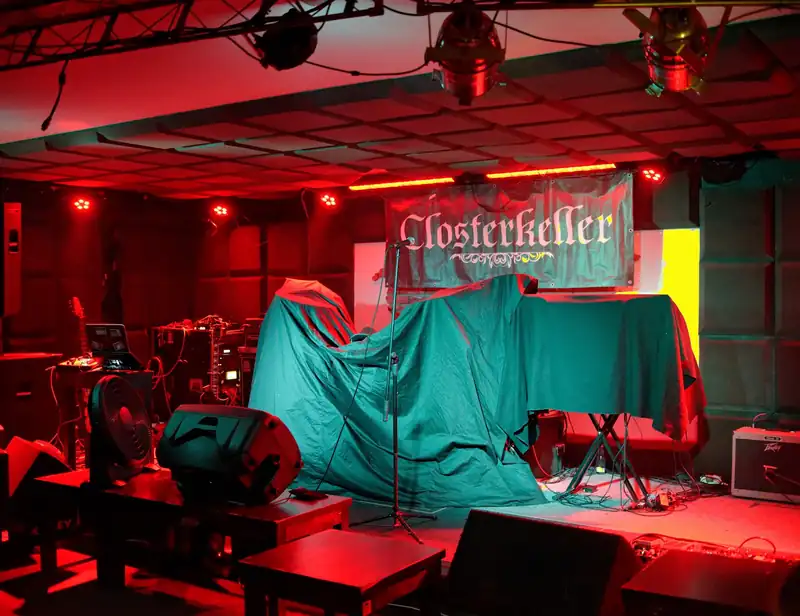 Scena przygotowana na koncert, czerwone światło i baner zespołu
